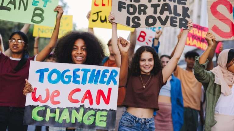 Multi cultural youth carrying home made signs about working together for change.